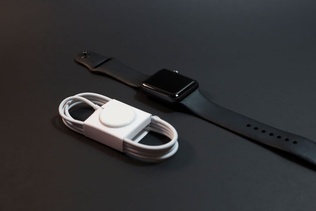 A smartwatch lying beside its magnetic charger