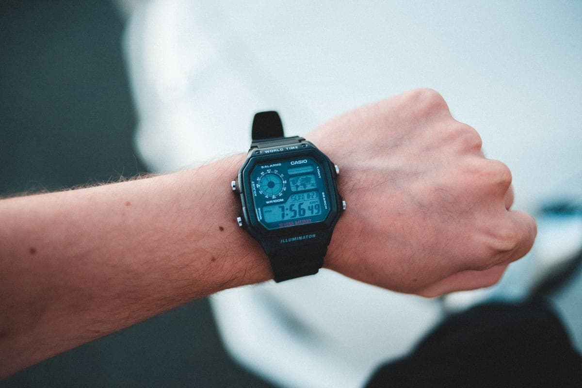 A black digital watch on a raised wrist