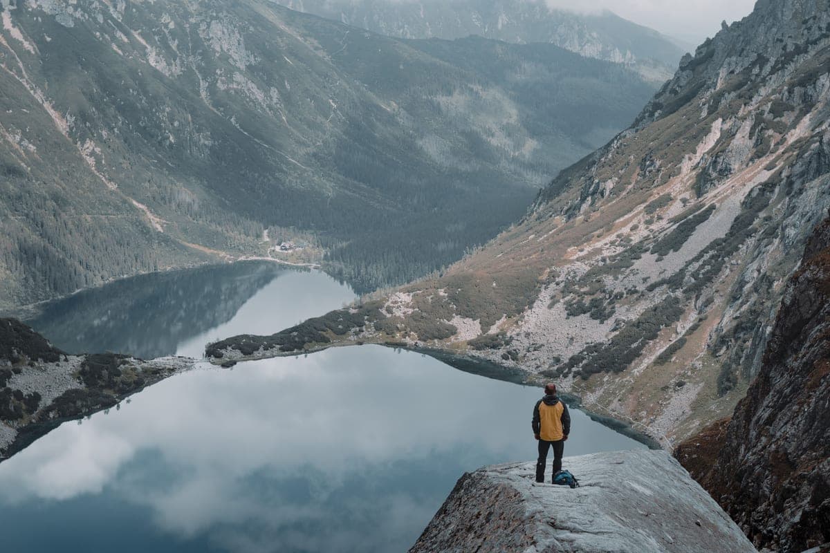 A hiker standing on a rock beside a mountain lake