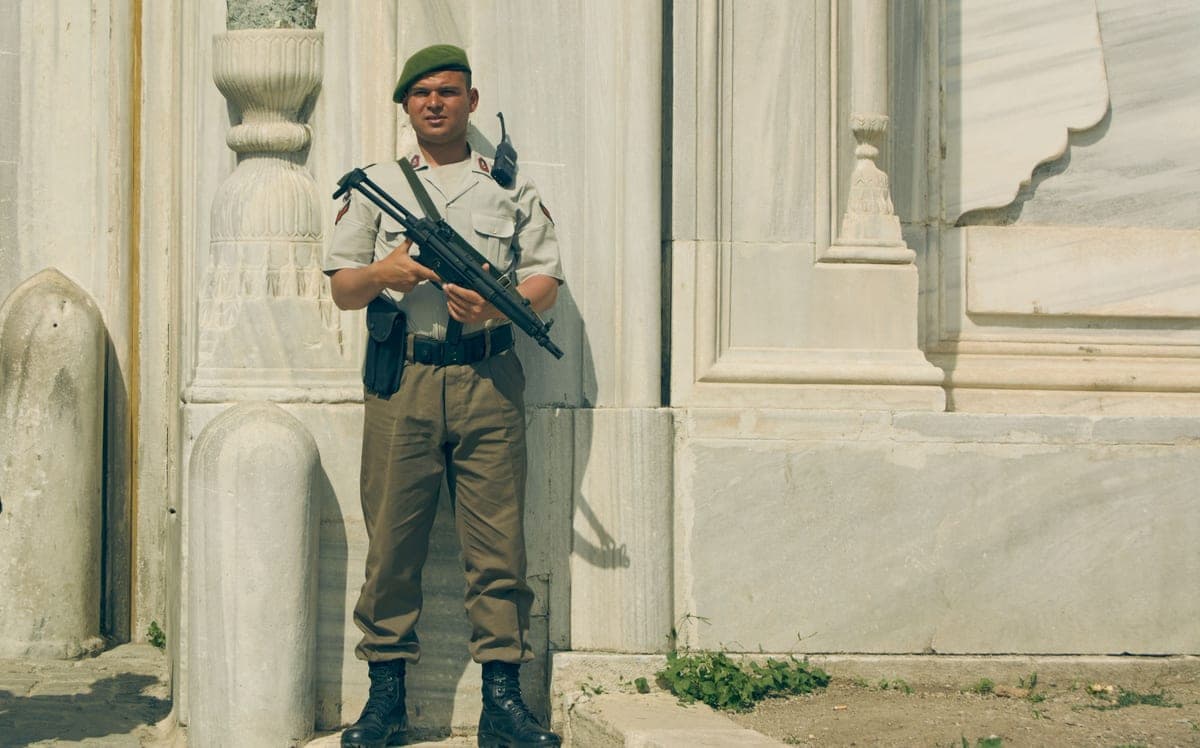 A soldier standing guard in uniform outside a stone building